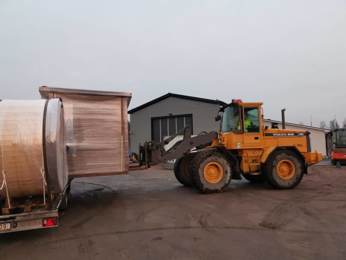 En lasthjuling från Volvo lastar ett paket med fabriksmålade paneler från en släpvagn.