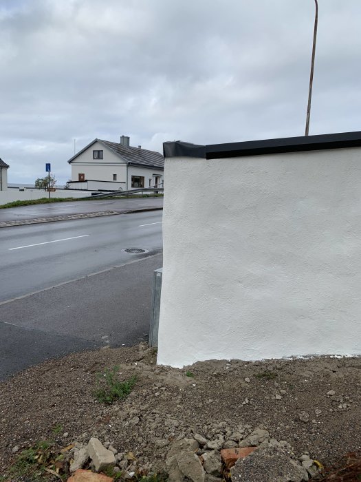Plåt böjd över hörnet på en vitmålad mur, med synlig ojämn böj nära en gata.