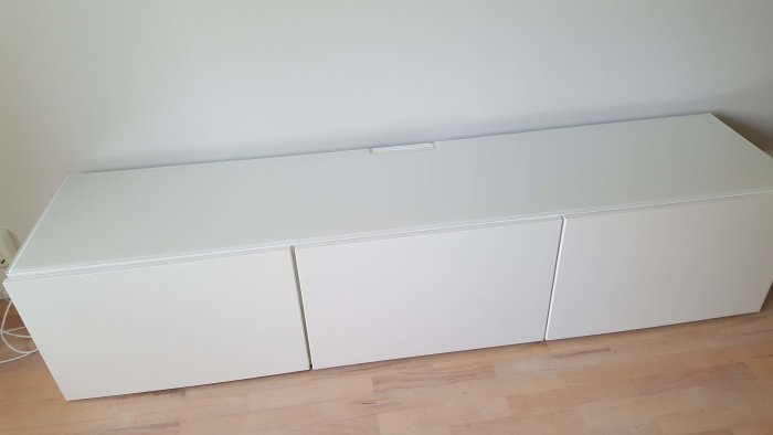 Vit IKEA tv-bänk i rum redo för ommålning, efter spackling och slipning.