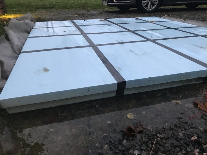 XPS-isolering på markduk och makadam anlagd för spabad, synlig vattensamling och lerjord i förgrunden.