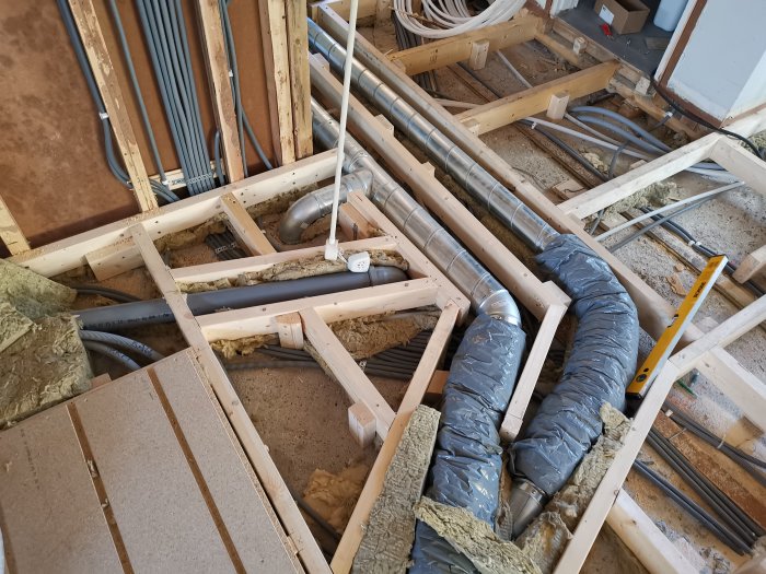 Nyreglat golv med isolering och synliga rörledningar i en pågående renovering.