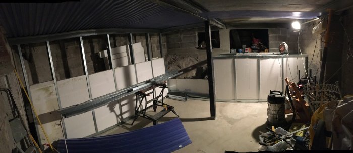 Utrymme under omvandling till verkstad, med isoleringsplattor och byggmaterial synliga.