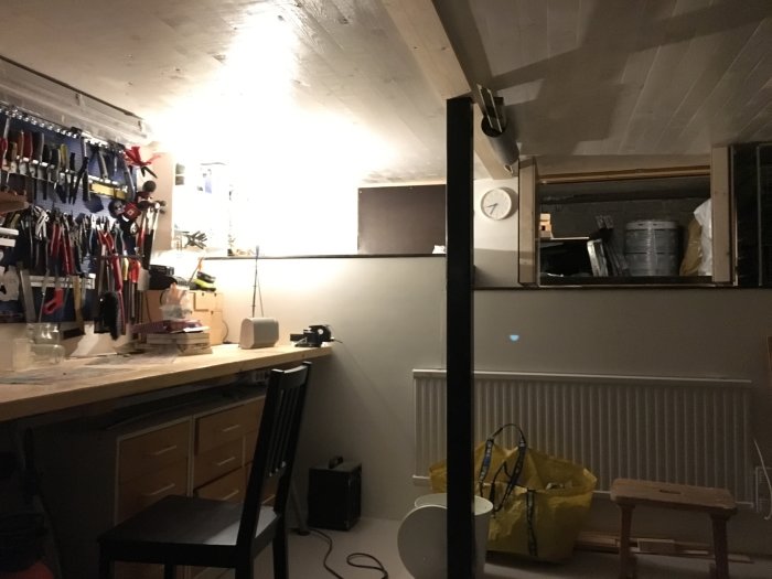 Inredd verkstad under en betong-altan med verktyg på väggen och arbetsbänk.