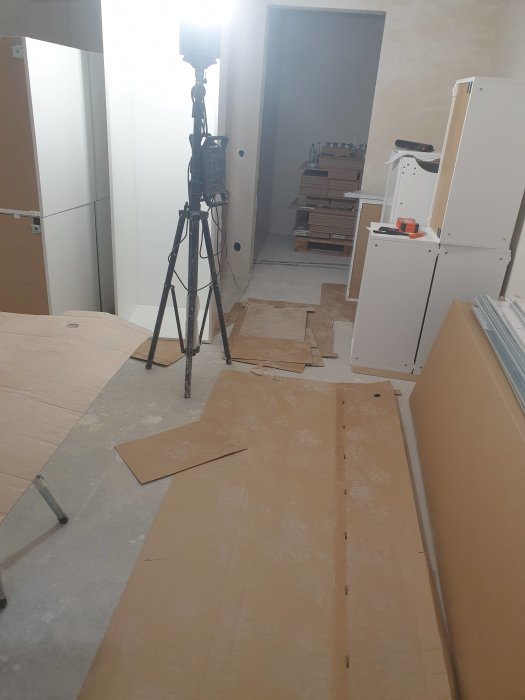 Ouppbyggda möbelpaket på golv med kamerastativ i ett halvfärdigt rum under renovering.