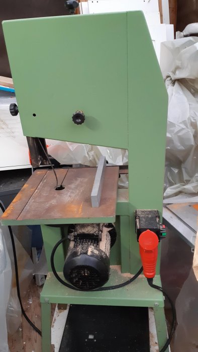 Gammal grön bänkmonterad bandsåg med 550W 3-fas motor och slitna bladstyrningar.