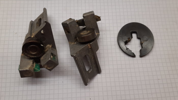 Gamla slitna sågbladsstyrningar och en trasig plastbricka från en äldre sågmodell på rutigt papper.