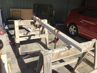 Arbetsbänkar med påklistrat laminat i en garageverkstad, verktyg synliga, med en röd bil i bakgrunden.