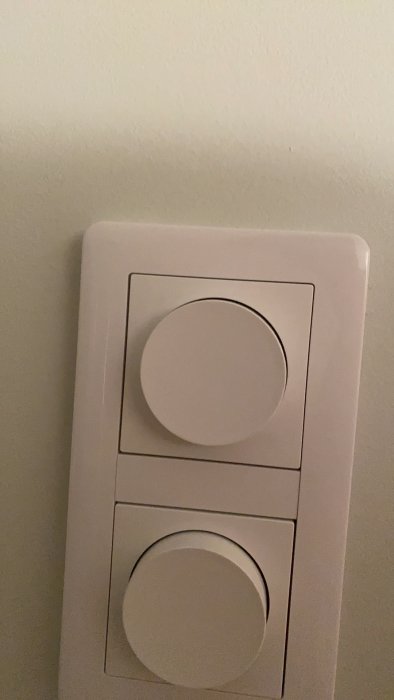 Dimmerbrytare på vägg; övre knapp verkar vara i avstängt läge och nedre är otydlig.