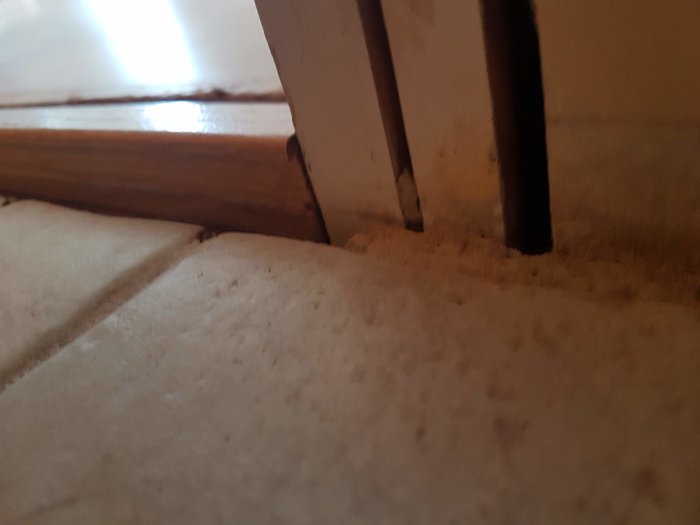 Nyjusterad tröskel som ligger mot en vägg, med det gamla golvet synligt och förberett för borttagning.