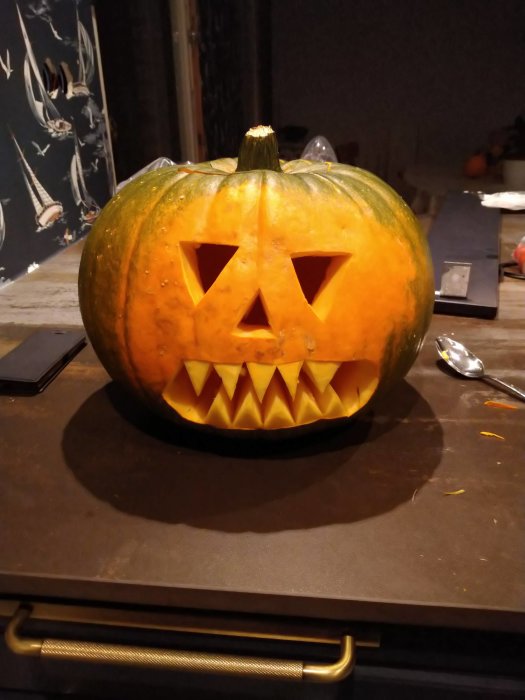 Utskuren pumpa med triangelformade ögon och tandad mun för Halloween på bord.