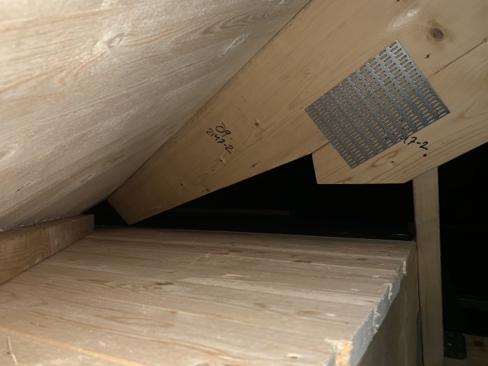 Inre hörn av takkonstruktion med synliga träreglar och råspont.