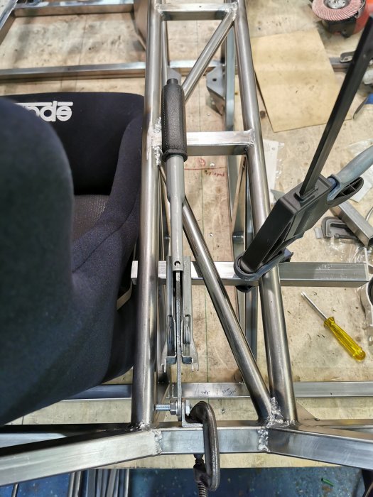 Svetsningsdetaljer på metallram med verktyg och stol i en verkstad.