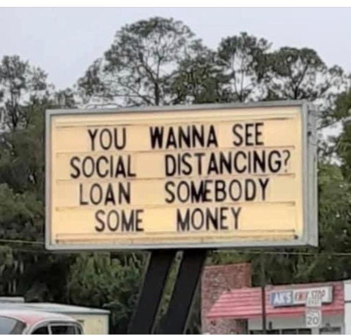 Skylt med texten "You wanna see social distancing? Loan somebody some money" mot träd och himmel.