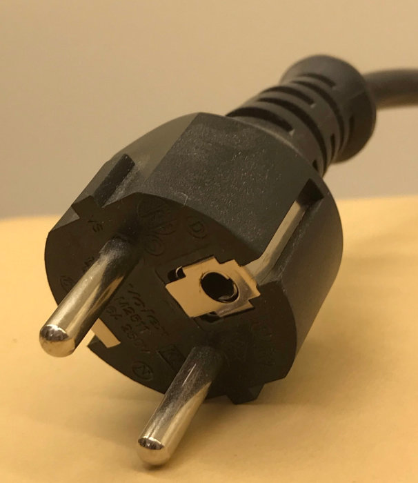 Elektrisk stickkontakt med utstickande jordstift i överkant och två platta stift nedtill.