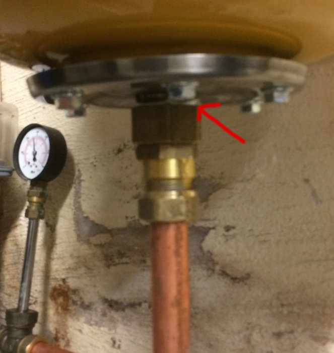 Kopparledning ansluten till en hydrofortank med en liten läckageindikerad av en röd pil, omgiven av gängtejp.