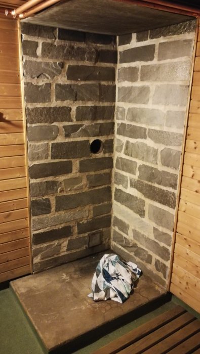 Bastuhörn av sten med ventilationshål och hopvikta handdukar på bänken.