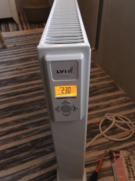 Lvi Yali digital radiator med inställd temperatur på 23 grader, displayen visas och en skruvmejsel på golvet.