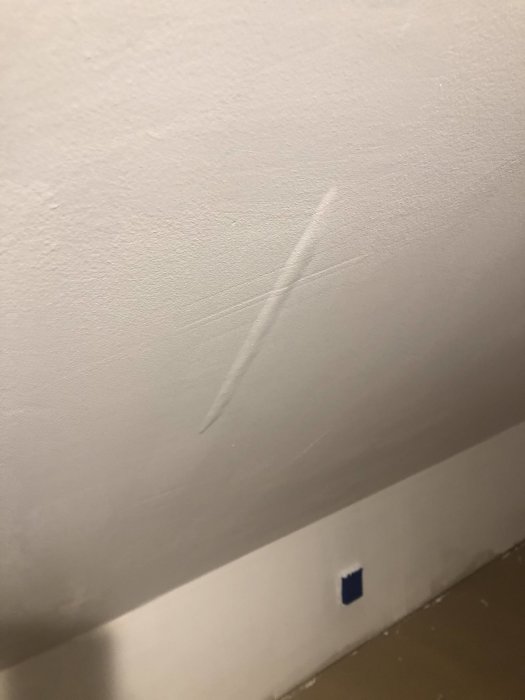 Ny målad gipsvägg med synliga pappremsor och bubblor efter spackling.