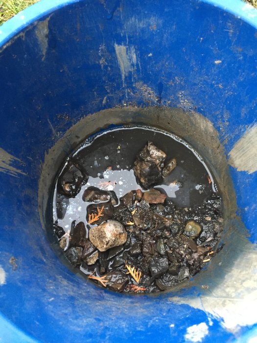 Avloppsbrunn fylld med småsten och skräp, tänkt att visa problemet med igensättning vid skyfall.