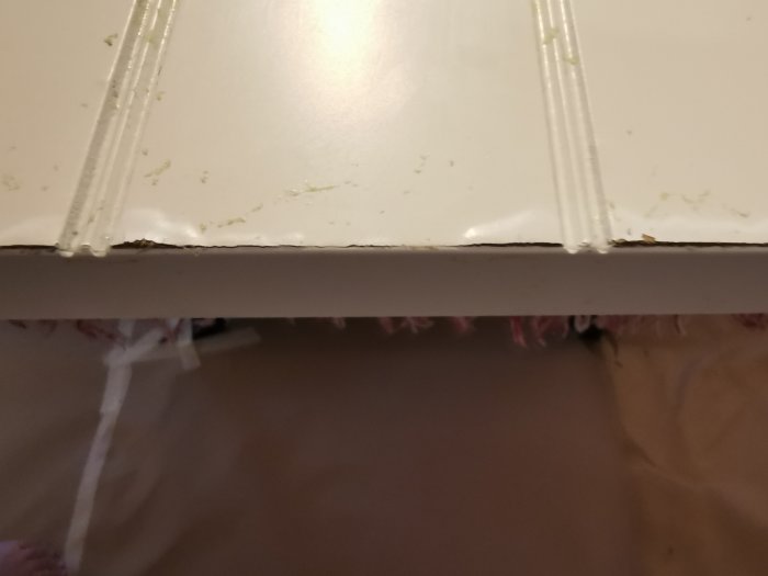 Skjutdörr med rester av spraylim och skadat faner där det bubblat samt synbart fjärmat material.