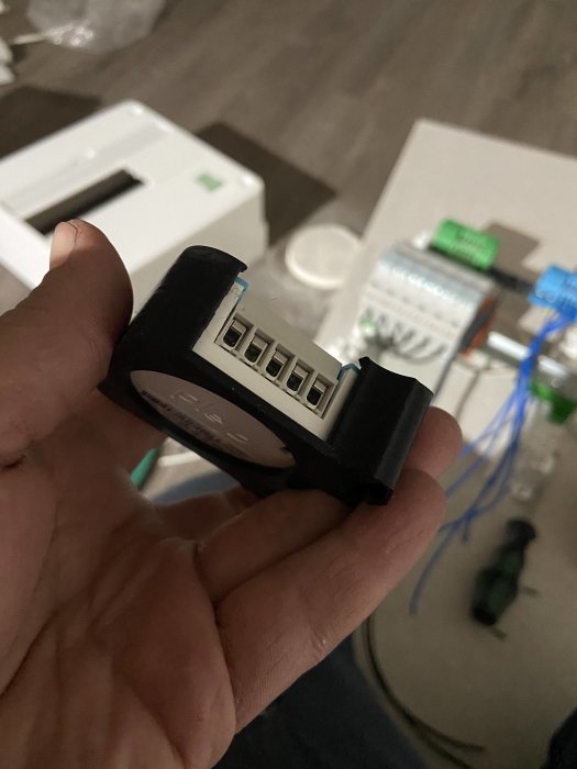 3D-utskrivet objekt med flera munstycken hålls i en hand, föremål för försäljning i bakgrunden.