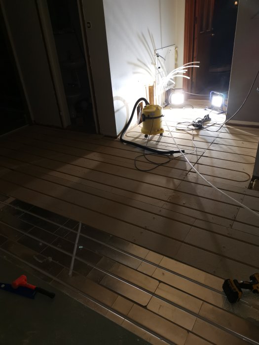 Installation av golvvärmeslangar på ett isolerat hallgolv med verktyg synliga.