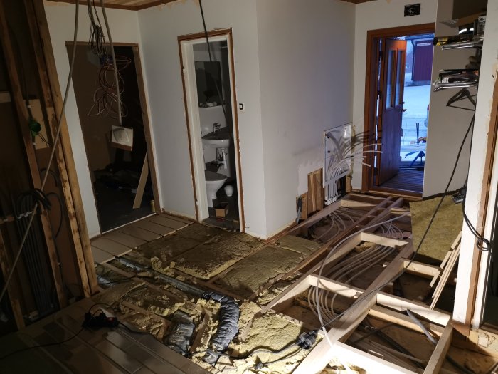 Installation av golvvärme med synliga rör och isolering i en under renovering hall.