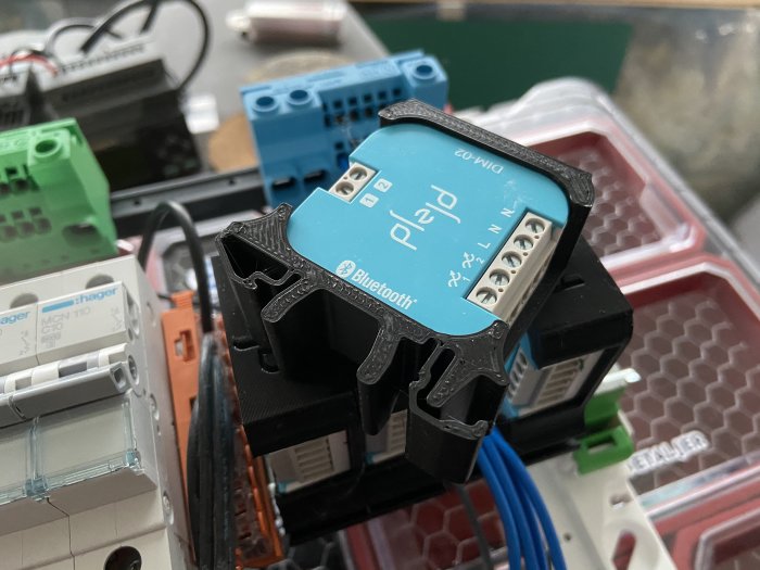 Elektrisk apparatur med blå plc-modul märkt med "Bluetooth" och kablar anslutna, omgiven av olika elektriska komponenter.