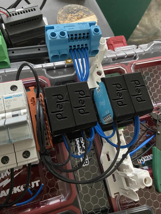 Elektriskt installationsskåp med brytare, säkringar och kopplade kablar.