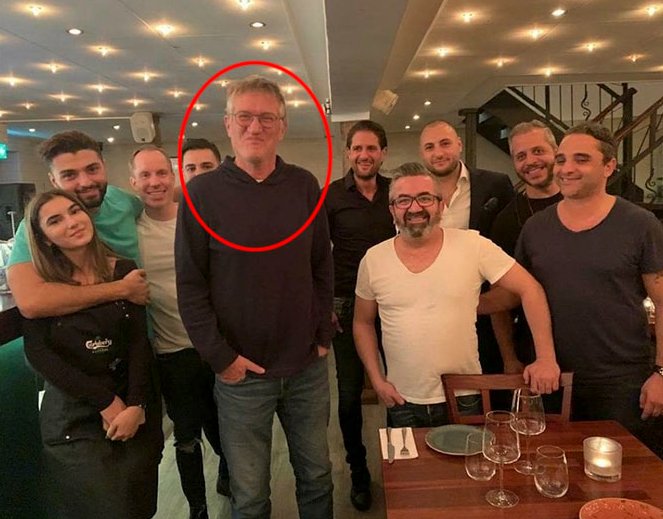 Grupp personer fotograferade inomhus, en man framhävs och står längre fram.