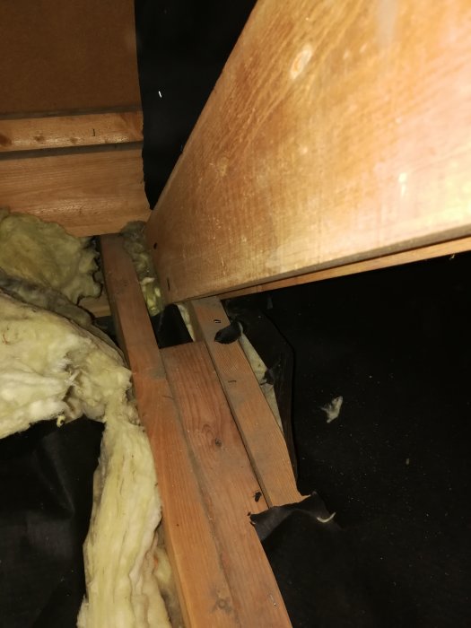 Bjälkar och isolering på vind med fokus på numrerad kapad mellanbjälke och närliggande trappa.