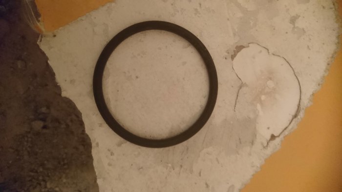 Gammal o-ring på ett betonggolv med rester av byggmaterial.