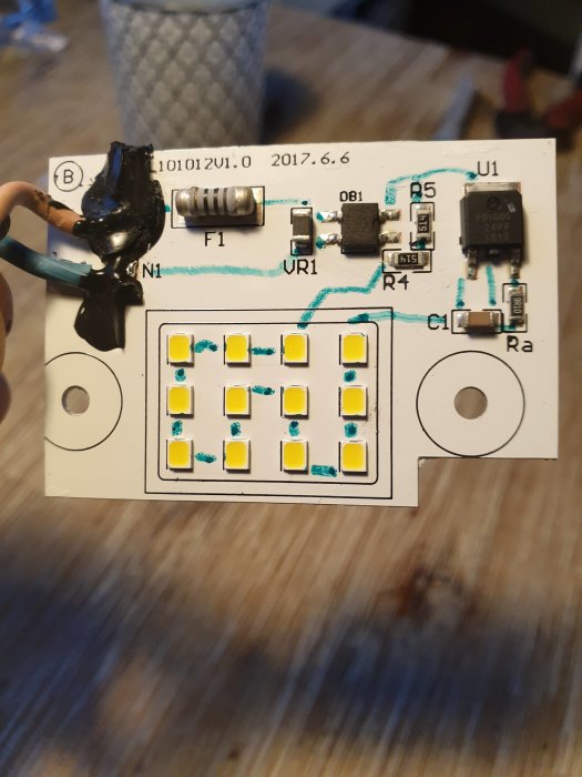 LED-lampaens kretskort med synliga komponenter och lödförbindelser, delvis skadad.