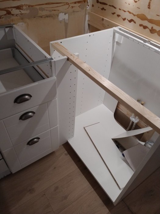 Process av köksrenovering med nya vita Ikea-skåp, ofärdigt under arbete, med synliga verktyg.