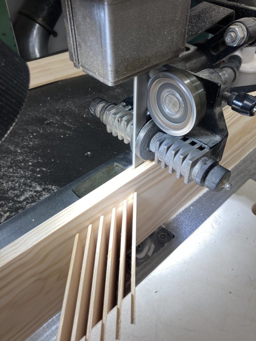 En featherboard i användning vid sågning av långa fanérbitar med en bandsåg.