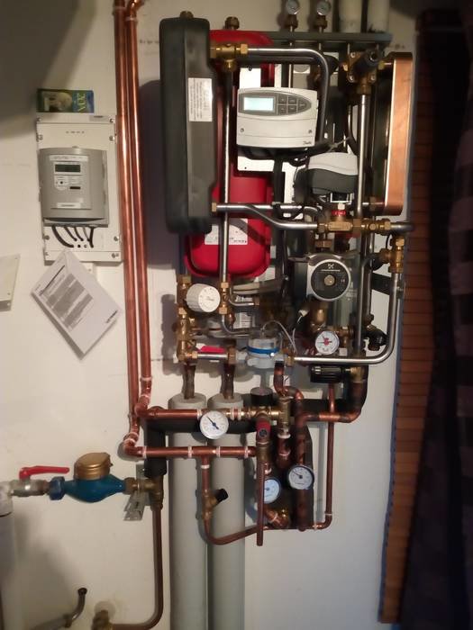 Installation av värmesystem med plattvärmeväxlare, termometrar, cirkulationspumpar och rörkopplingar i ett pannrum.