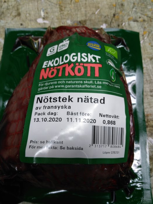 Ekologiskt nötkött i nätpackning med etikett som visar bäst före-datum och vikt.