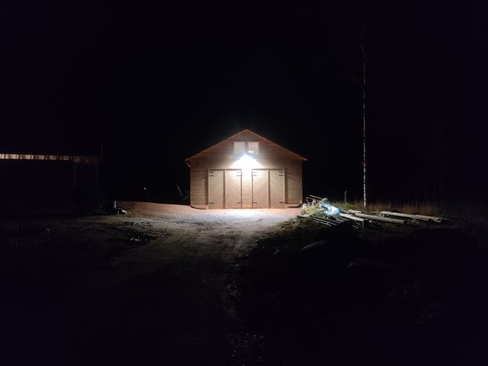 Garage upplyst av en nyinstallerad LED-armatur med behagligt ljus i mörkret, belyser området framför utan spill.