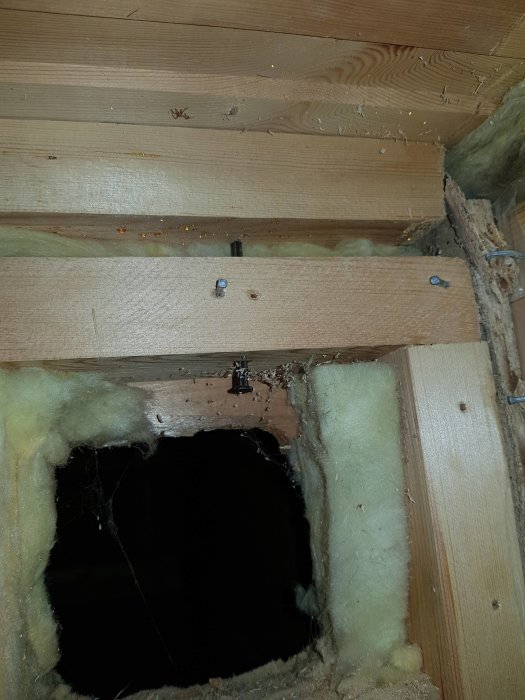 Innertak i timmerstuga med synlig isolering och träkonstruktion, inklusive öppning för installation.