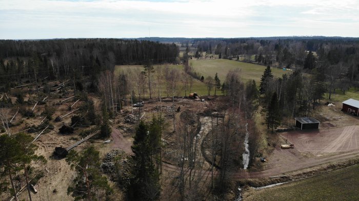 Drönarbild av ett pågående byggprojekt med golvplatta och omgivande avverkade träd.