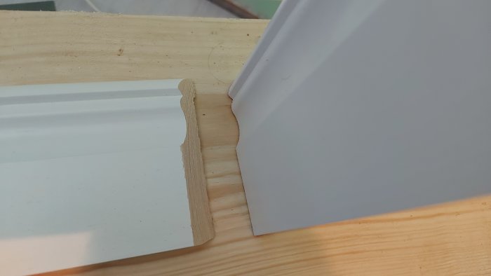 Närbild av en hörninstallering av allmogelister på nylagt laminatgolv.