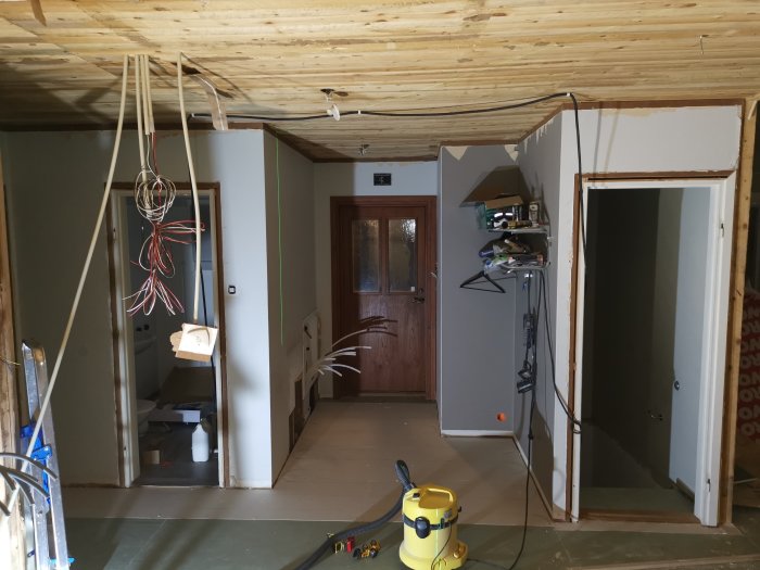 Renoveringsarbete i rum under konstruktion med exponerade ledningar och olikfärgat golvgips.
