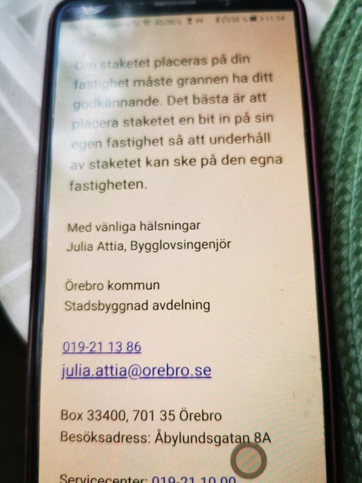 E-post från Örebro kommuns bygglovsingenjör på en smartphone om placering av staket på fastighetsgräns.
