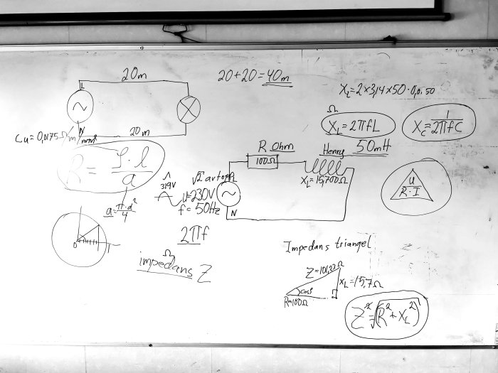 Svartvit bild på en whiteboard fylld med handskrivna matematiska formler och diagram relaterade till elektricitet.