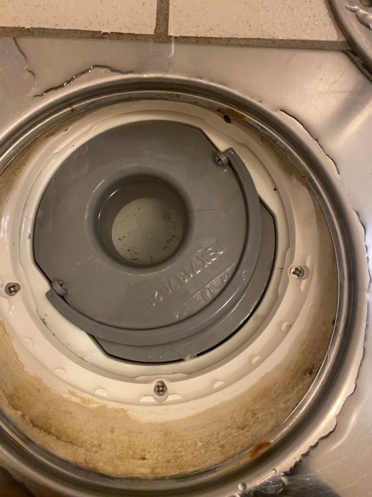 Närbild på ett vattenlås i ett handfat med ett märkbart glapp mellan vattenlåset och kanten.