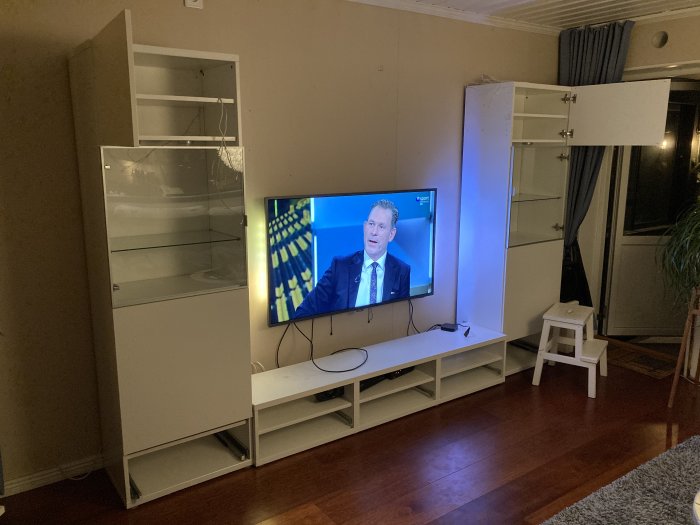 Vardagsrum redo för renovering med halvtomma Bestå-möbler och en pågående TV på skärm.