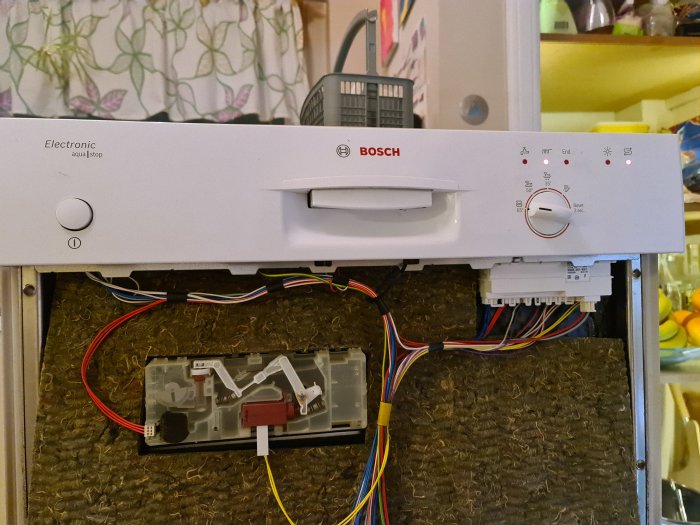 Öppen frontpanel på en BOSCH diskmaskin som visar elektronik och kabelanslutningar.
