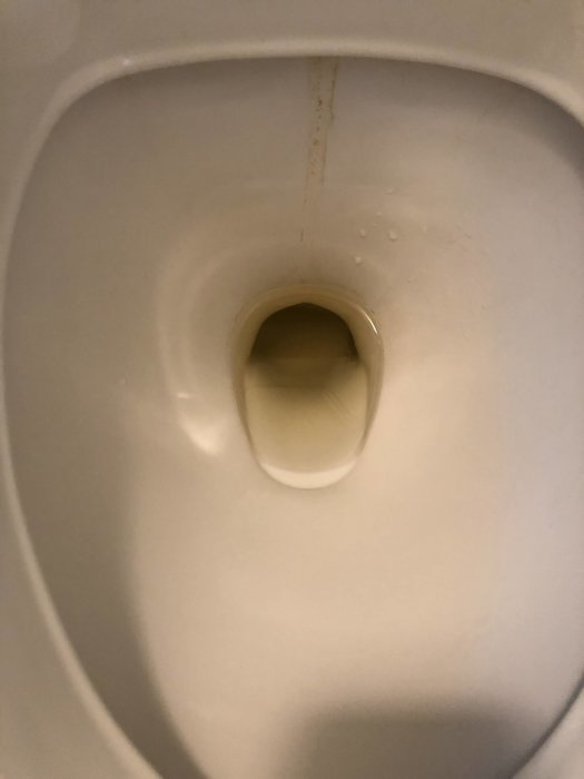 Rostfärgad kalkavlagring i toalettskål som indikerar vattenproblem relaterade till rörinstallationer.