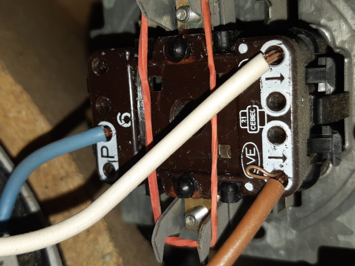 Elanslutningar inuti en elektrisk strömbrytare med märkta kablar och skruvanslutningar.