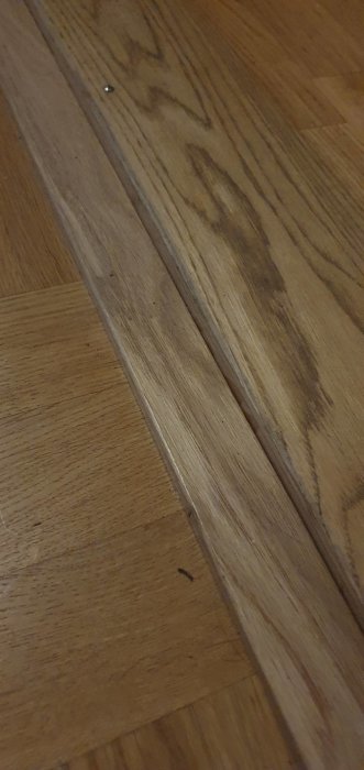 Tröskellist installerad på trägolv vid övergång mellan rum.